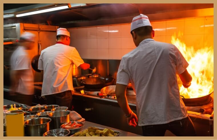 厨房で料理をしている中国人スタッフのイメージ